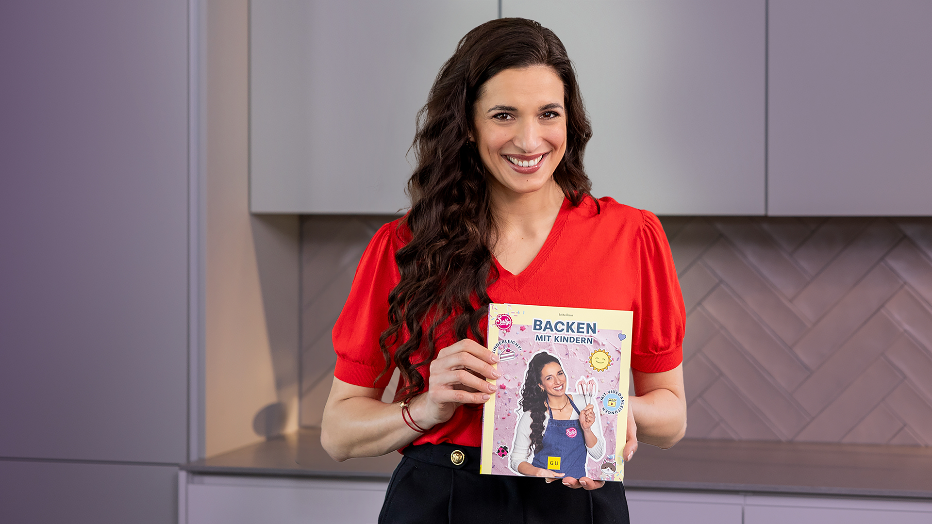 Sally hält das Buch: Sallys Backen mit Kindern in der Hand